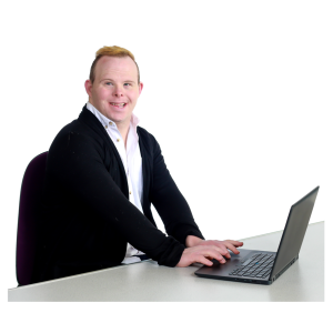 A person sitting at a desk, smiling, and working on a laptop.