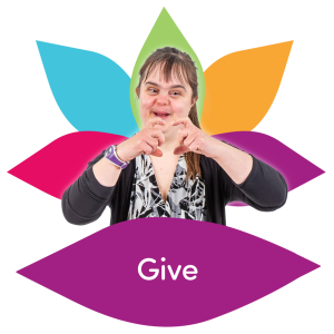 Woman with Down syndrome making a heart gesture with her hands in front of a colourful lotus flower.